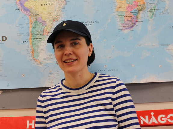 Tjej i keps och randig tröja framför en världskarta