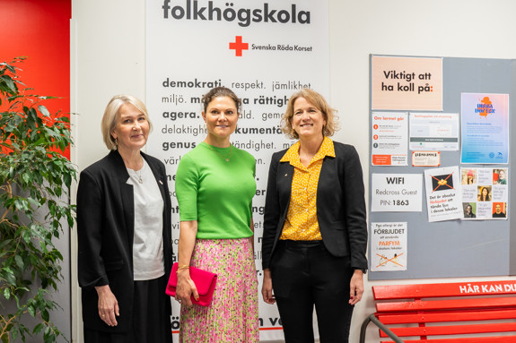 Kronprinsessan Victoria med Röda Korsets folkhögskolas rektor samt generalsekreteraren för Svenska Röda Korset. De poserar på skolan framför en vepa med folkhögskolans och Röda Korsets värdeord.