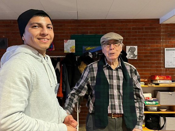 En deltagare från folkhögskolan står tillsammans med en senior som deltar i seniorverksamheten
