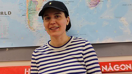 Korthårig tjej i keps och randig tröja framför en världskarta