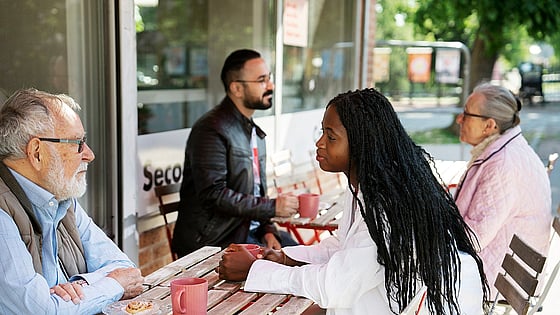 Människor med olika ålder och bakgrund samtalar på ett café