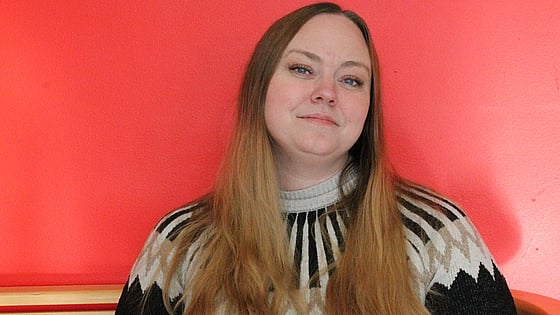 Närbild på nöjd tjej i långt hår med röd bakgrund