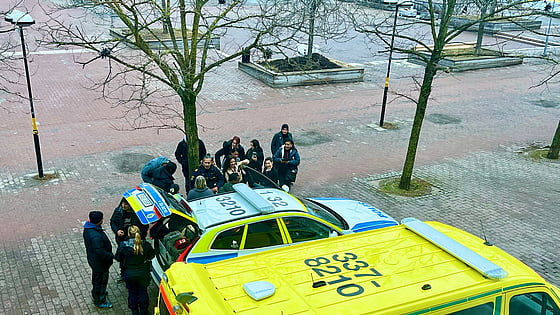 Bild från Blåljusdagen 2024. Deltagare står samlade runt en polisbil och en ambulans. Två poliser berättar om bilen och polisyrket.
