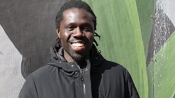 Glad vuxenstudent i solen med väggmålning som fond