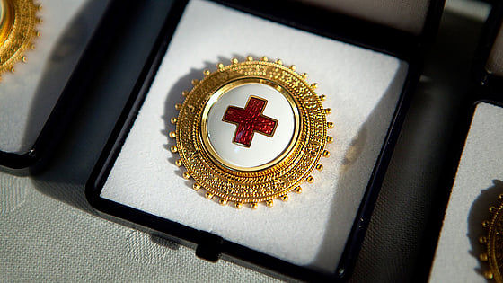 En sjuksköterskebrosch med Röda Korsets symbol ligger i en ask