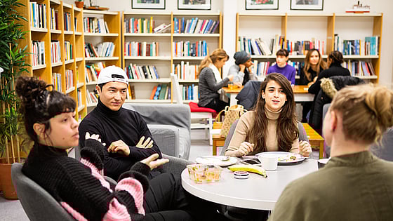 Deltagare sitter vid olika bord i skolans kombinerade bibliotek och fikarum "bibliofiket"