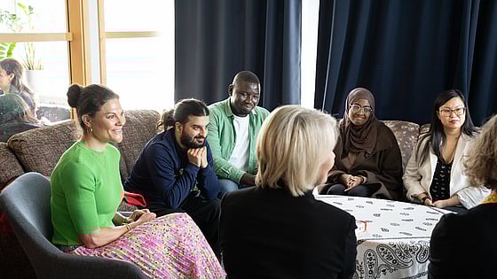 Kronprinsessan Victoria samtalar med några deltagare från folkhögskolan. De sitter i en soffgrupp och är glada.