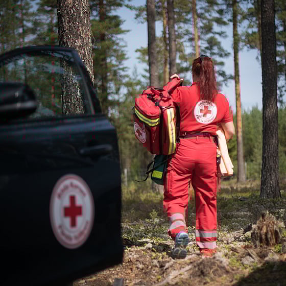 En kvinna stegar in i skogen med krisutrustning vid skogsbrand