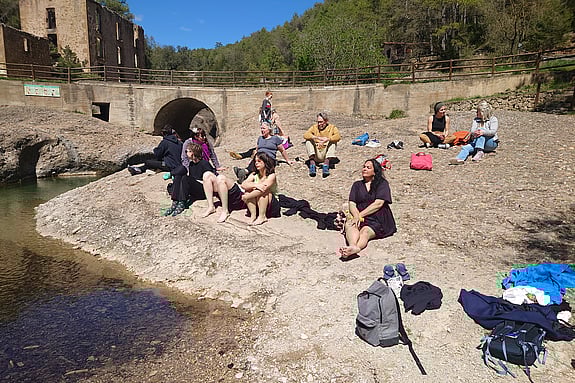 En paus i resandet. Ett gäng kursdeltagare sitter och njuter av solen på en stenstrand i södra Europa
