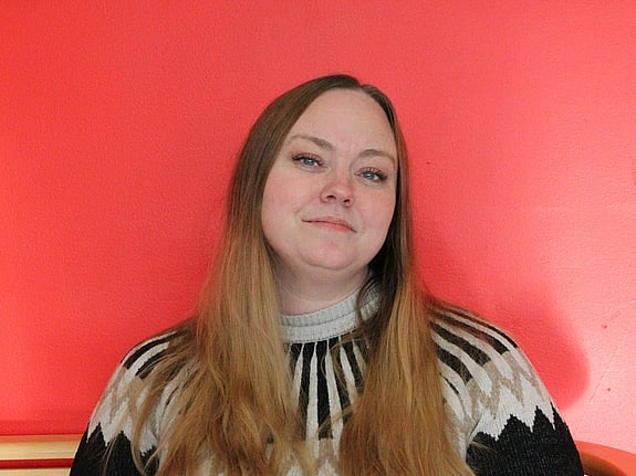 Närbild på nöjd tjej i långt hår med röd bakgrund