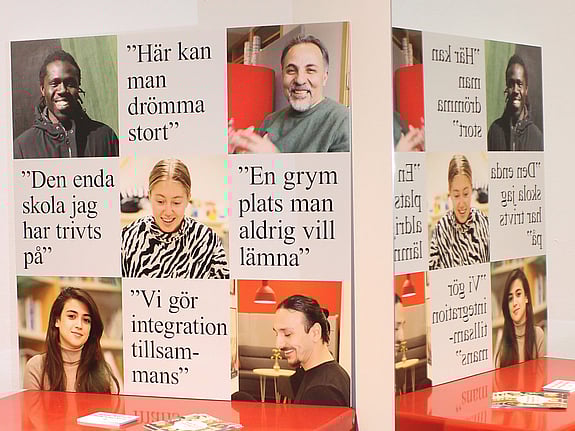 Bilden visar en vägg med en vepa med värdeord för Röda Korsets folkhögskola, en anslagstavla med olika affischer och en röd parksoffa