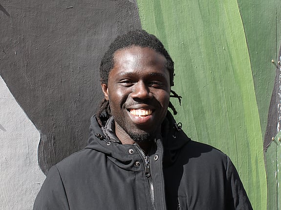 Glad vuxenstudent i solen med väggmålning som fond