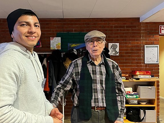 En deltagare från folkhögskolan står tillsammans med en senior som deltar i seniorverksamheten