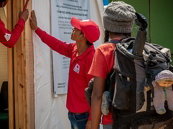 På flykt i Panama. Flicka med ryggsäck får rent vatten av volontärer från Röda Korset