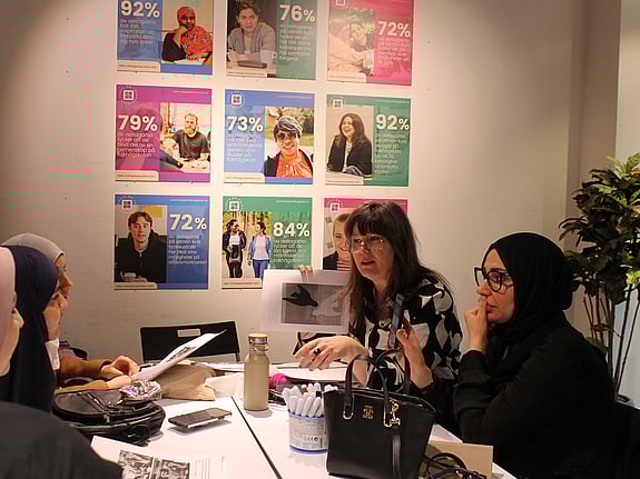 En grupp med deltagare lyssnar på en lärare som ger instruktioner vid en workshop