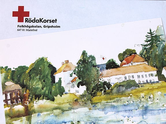 Foto av en akvarell föreställande Röda Korsets folkhögskola i Gripsholm. Äldre vita byggnader vid vattnet och en flagga med ett rött kors som vajar mellan grönskande träd.