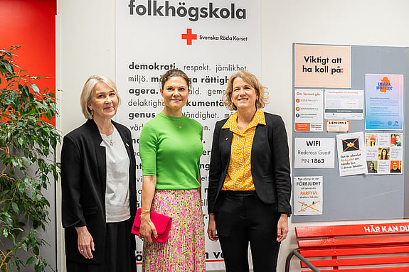 Kronprinsessan Victoria med Röda Korsets folkhögskolas rektor samt generalsekreteraren för Svenska Röda Korset. De poserar på skolan framför en vepa med folkhögskolans och Röda Korsets värdeord.