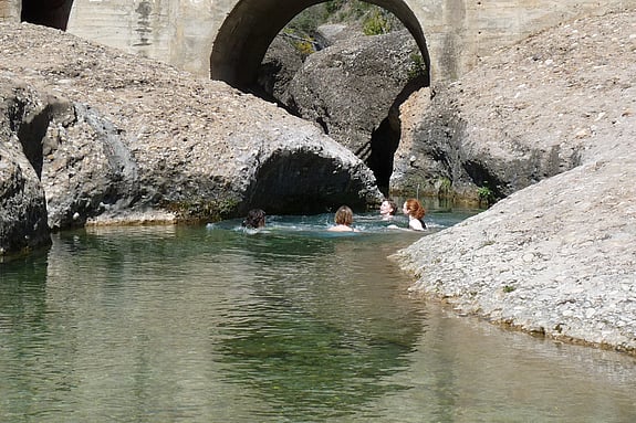 Några kursdeltagare på kursen i hållbart resande badar i grönt vatten i en lagun mellan två mindre berg