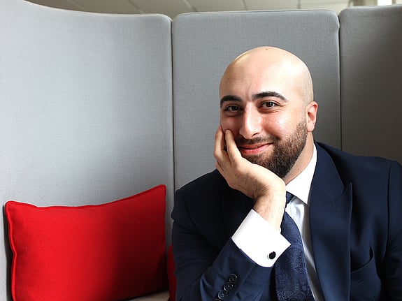 En nöjd deltagare från Röda Korsets folkhögskola som precis fått sin gymnasiebehörighet. Det är ett porträtt av en ung leende man med hakan i handen.