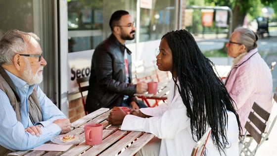 Människor med olika ålder och bakgrund samtalar på ett café