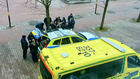 Bild från Blåljusdagen 2024. Deltagare står samlade runt en polisbil och en ambulans. Två poliser berättar om bilen och polisyrket.