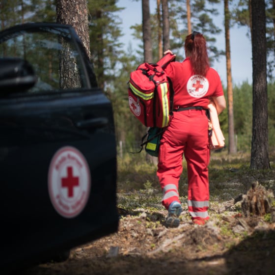 En kvinna stegar in i skogen med krisutrustning vid skogsbrand