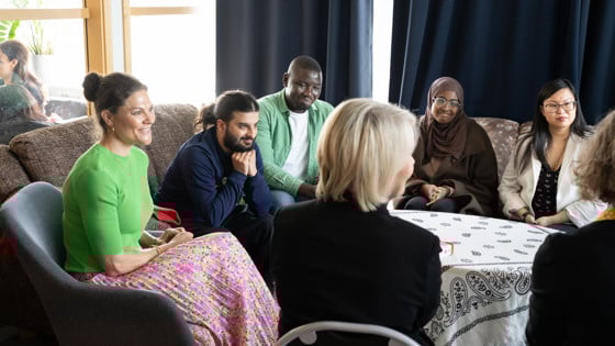 Kronprinsessan Victoria samtalar med några deltagare från folkhögskolan. De sitter i en soffgrupp och är glada.
