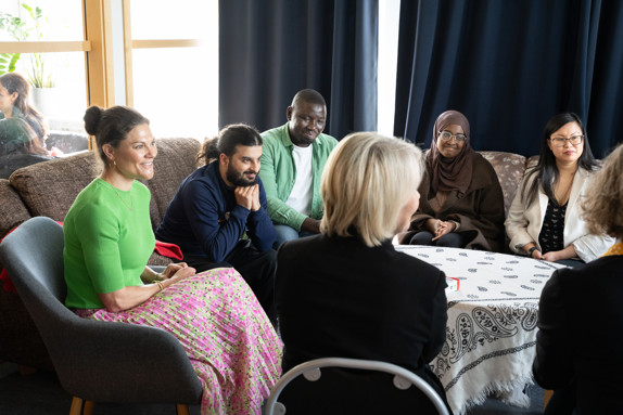 Kronprinsessan Victoria samtalar med deltagare från Röda Korsets folkhögskola. De sitter i en soffgrupp och är glada och intresserade av varandra.