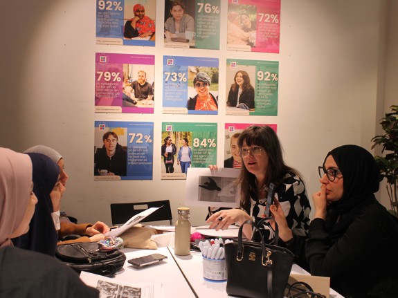 En grupp med deltagare lyssnar på en lärare som ger instruktioner vid en workshop