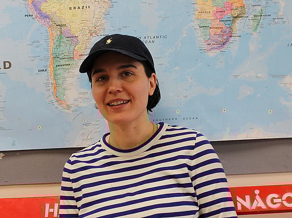 Tjej i keps och randig tröja framför en världskarta